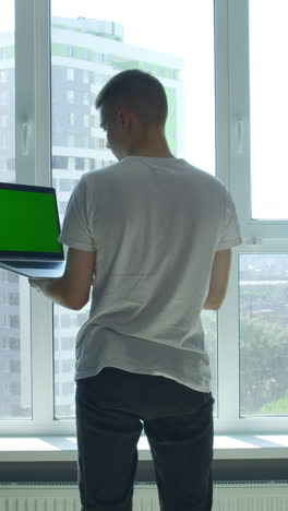adolescente trabajando en una computadora portátil junto a la ventana