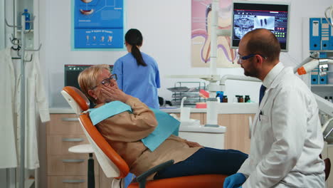 old patient touching cheek showing tooth with pain