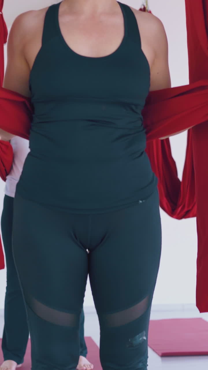 pretty ladies lie on special long anti-gravity hammocks and relax after advanced yoga workout close view