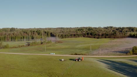 drone side follow shot of a tractor in a field. verdant countryside farmland.