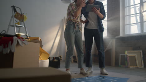 una pareja sonriente planea la reparación del hogar con una tableta. la familia se queda en la nueva casa.