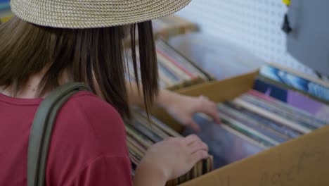 Close-up-of-girin-hat-looking-through-old-vinyl-records-in-market