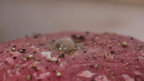 macro close-up of a raw seasoned hamburger patty as the center bubbles while it cooks