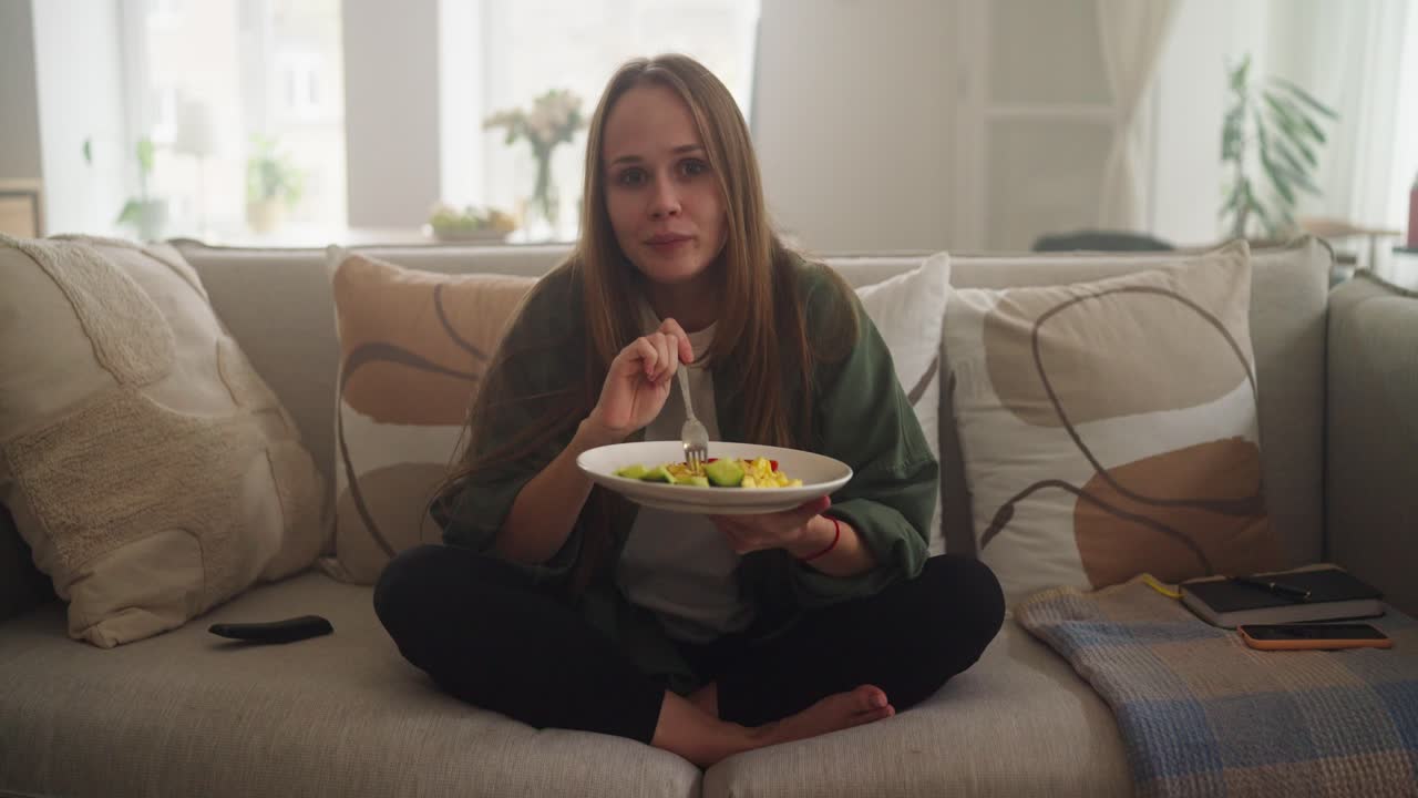 mujer comiendo ensalada en el sofá