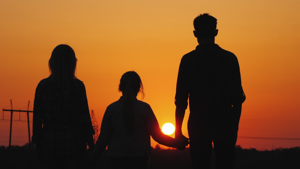 도시 후면의 주황색 일몰을 감상하는 세 가족
