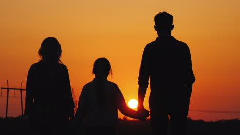 Familia-De-Tres-Admirando-La-Atardecer-Naranja-Sobre-La-Vista-Trasera-De-La-Ciudad