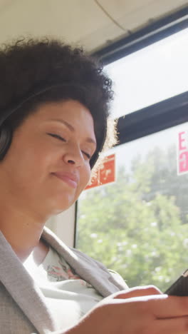 happy plus size biracial woman using smartphone in bus