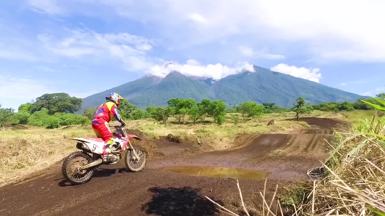Motocross riding in a rural landscape with a mountain in the background