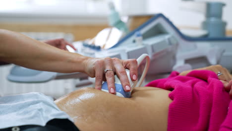 female doctor's hand moving the ultrasound device by the patient's belly. ultrasonic pregnancy scanning.