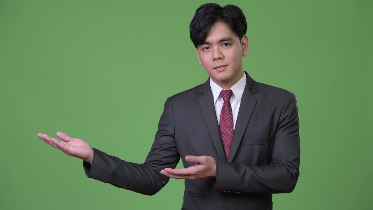 Young handsome Asian businessman showing something