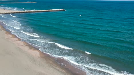 Wunderschöne-Blaue-Meereswellen,-Die-Mit-Panoramablick-Auf-Das-Ufer-Treffen---Vorwärtsbewegung-Und-Schwenken-Aus-Der-Luft