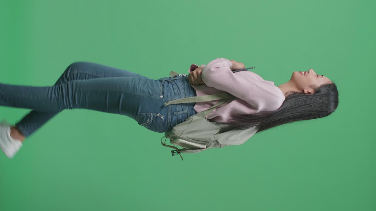 웃는 아시아 여성 학생이 태블릿을 들고 녹색 스크린 스튜디오에서 는 측면 시각