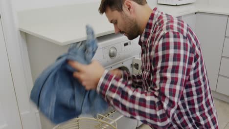 Man-removing-cloths-from-washing-machine-in-a-comfortable-home-4k