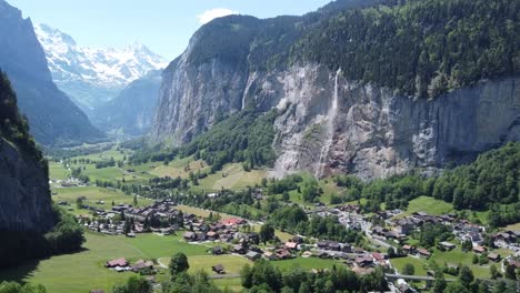 drone flight through the green valley of lauterbrunnen with a view of the beautiful waterfall and the snow-covered swiss alps in the background
