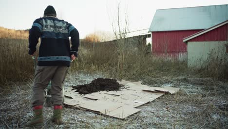 a man is moving soil onto the cardboard to use as mulch - static shot