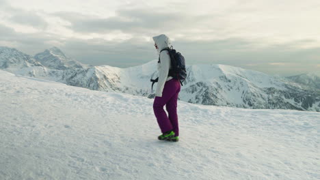 woman hikes on the snow-covered mountain during winter. - wide shot