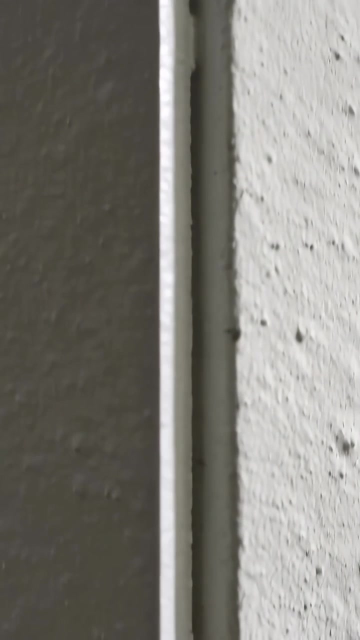 Wideo pionowe: Przesuwająca się kamera pokazująca listwę wykończeniową przy łączeniu ścian po przesunięciu kadru, sprawdzająca drobinki.