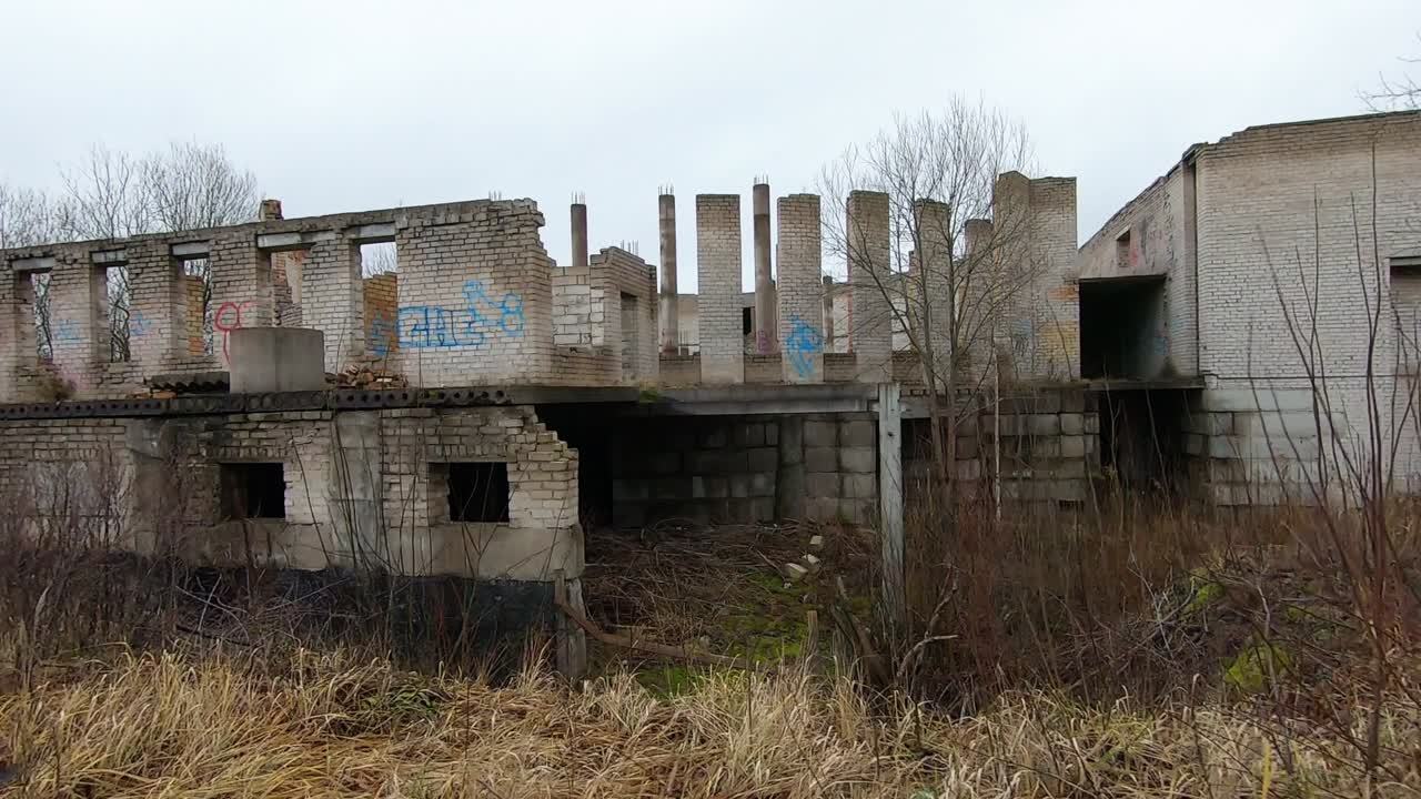 Abandoned White Brick Building Between Shrubs. Track Right Slow Motion Shot
