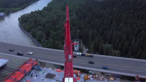Crane-by-busy-highway-bridge-construction-zone-from-above-circling