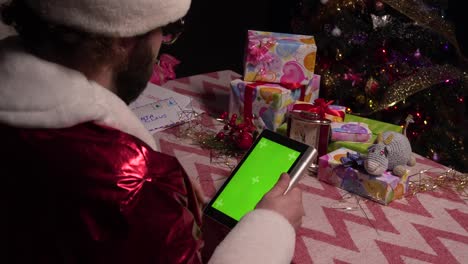 santa claus está usando la pantalla verde de la tableta para comprar. tableta con una pantalla verde.4k