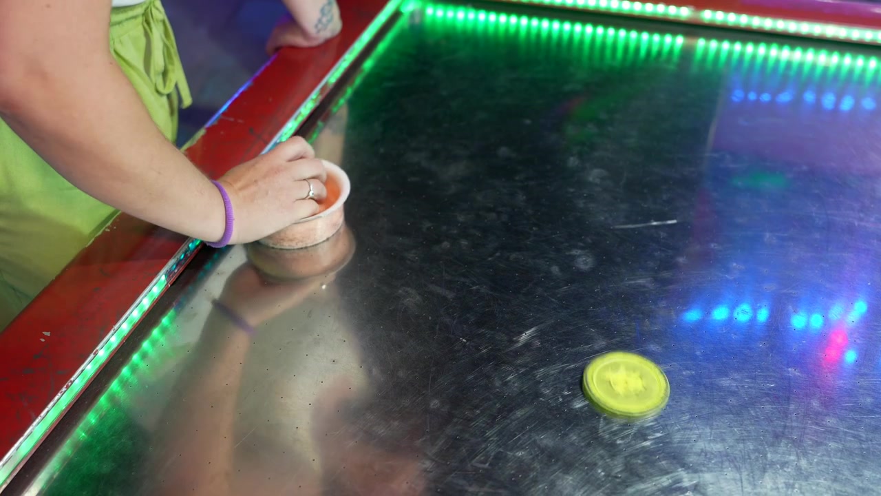 Persona che gioca a air hockey su un tavolo illuminato