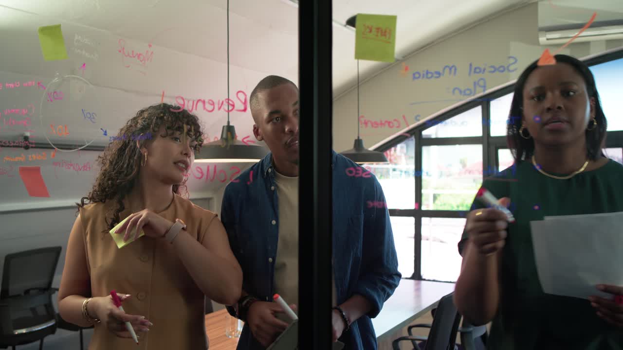 African American team pointing at glass notes in office, driving planning with markers and stickies