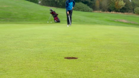 Verschwommener-Golfer,-Der-Sich-Für-Einen-Mittellangen-Putt-Anstellt,-Mit-Fokus-Auf-Das-Loch