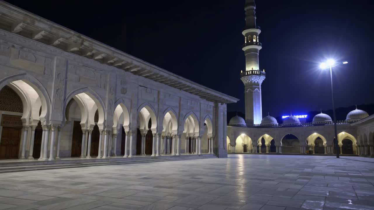 Majestic arches and columns illuminated at night create a tranquil atmosphere, highlighting the beauty of Islamic architecture in a modern mosque