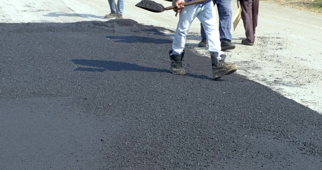 Operai sono impegnati a posare una strada asfaltata, mostrando lavoro di squadra e dedizione