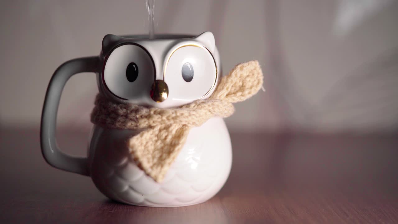 una taza de búho macro pequeña y linda cierra los ojos después de verter agua caliente
