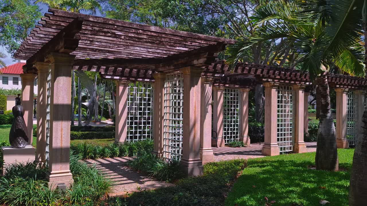 Pérgola decorativa con columnas y celosía en un exuberante jardín en Palm Beach, Florida