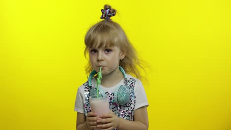 stylish child drinking milk cocktail through straw and showing thumb up. cold milkshake drink