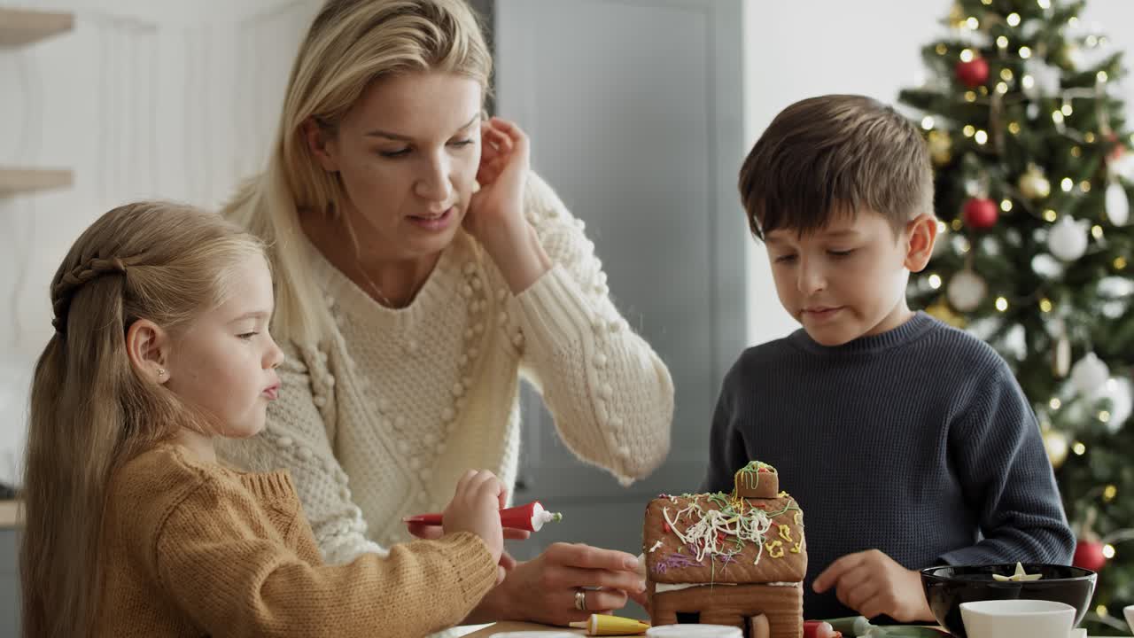 Video of children and mother decorating gingerbread house