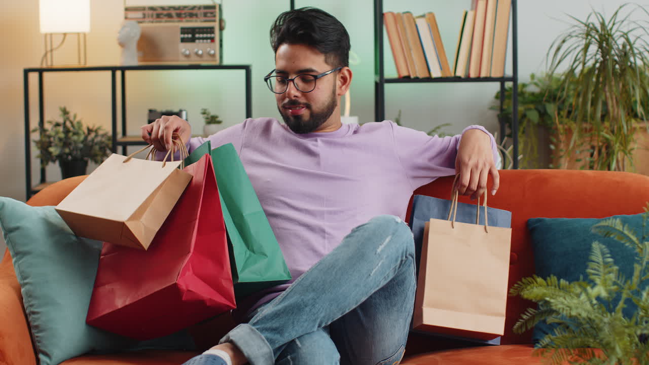 hombre indio feliz adicto a las compras consumidor regresó a casa después de la venta de compras en línea con bolsas en casa