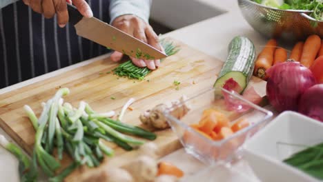 Mid-section-of-asian-senior-woman-chopping-vegetables-in-the-kitchen-at-home