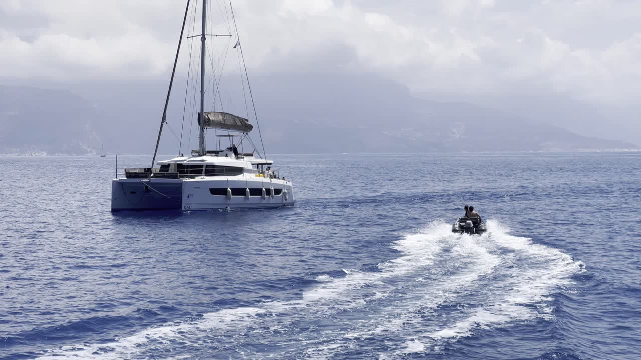 Catamaran anchored with motor tender on cloudy seascape