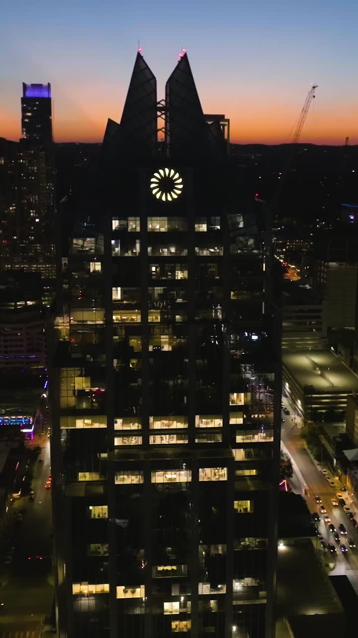 Portrait drone shot circling the Illuminated Frost bank tower, dusk in Austin, USA