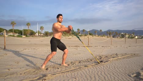 atleta musculoso entrenando ejercicios funcionales y básicos realiza arrastre en la playa con peso al amanecer