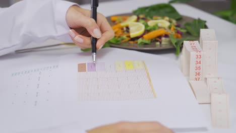 la dietista está preparando una dieta de vegetales para sus pacientes en la mesa.