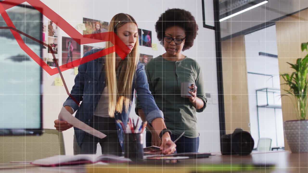 Business co-workers placing docs on table and analyzing falling metrics with red line-graph overlay