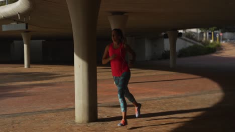 mujer caucásica corriendo debajo de un puente