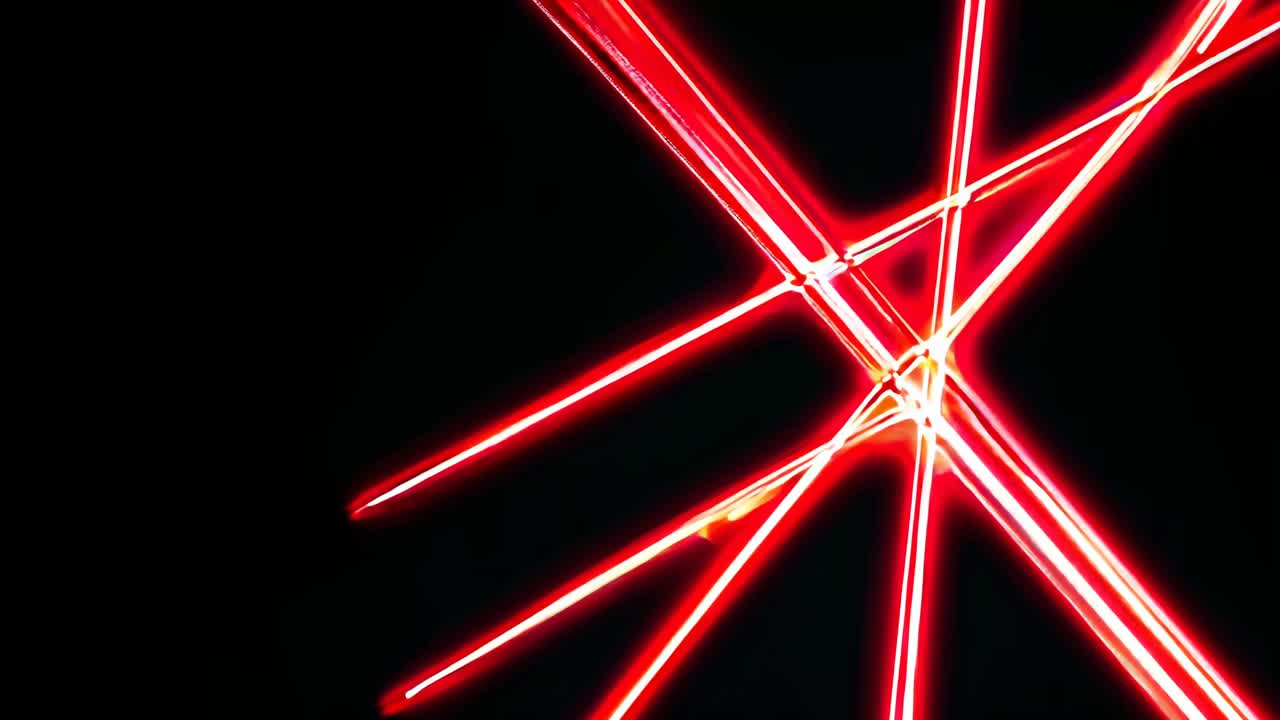 Dynamic video of intersecting red laser beams against a black background, captured from a low angle