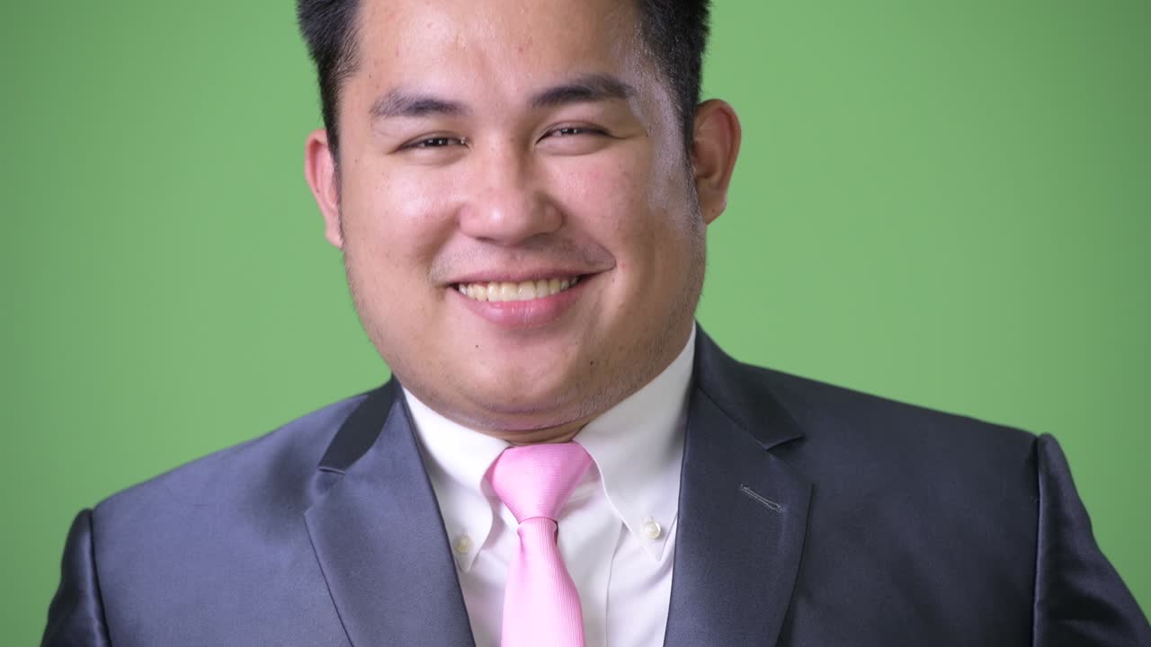 초록색 배경에 젊은 잘생긴 과체중 아시아 사업가