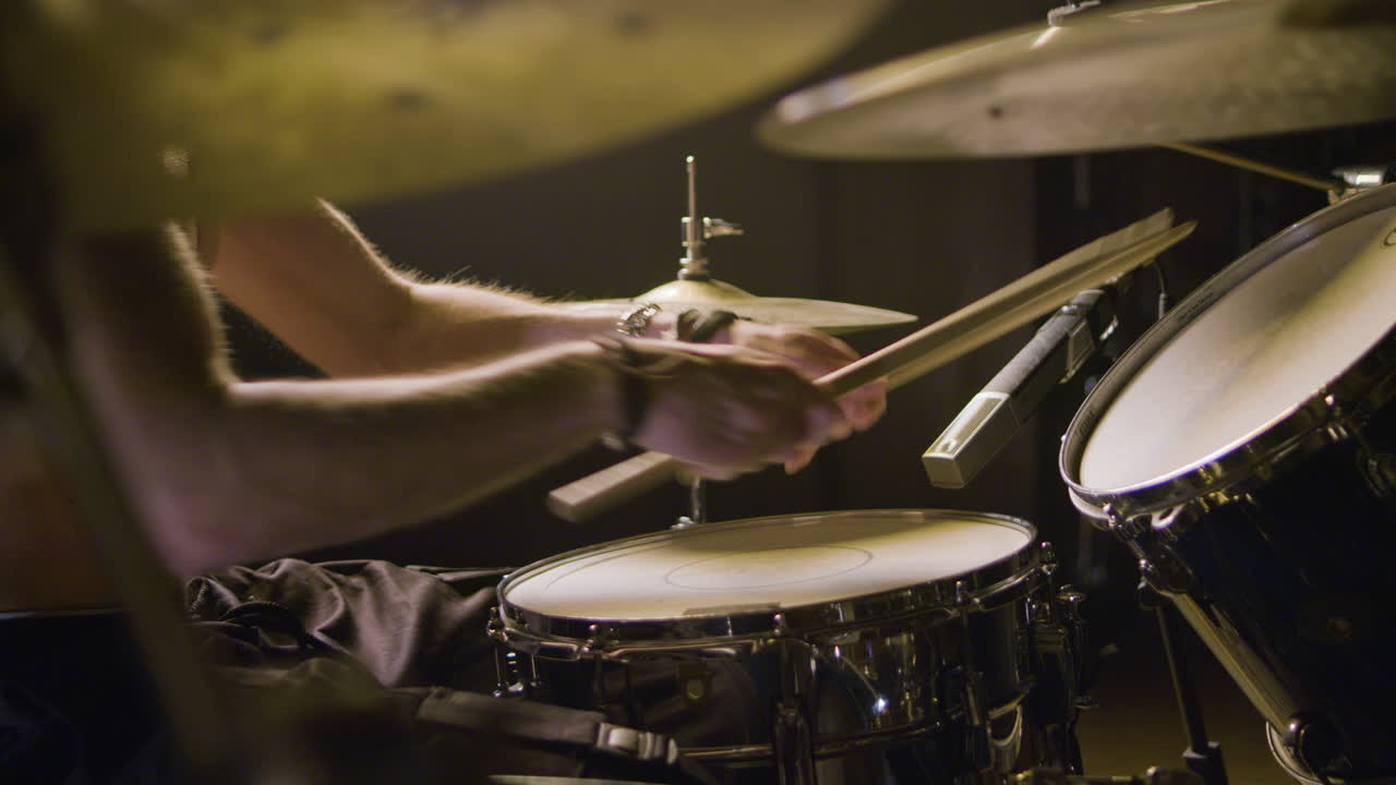 Young male drummer playing drums at music studio