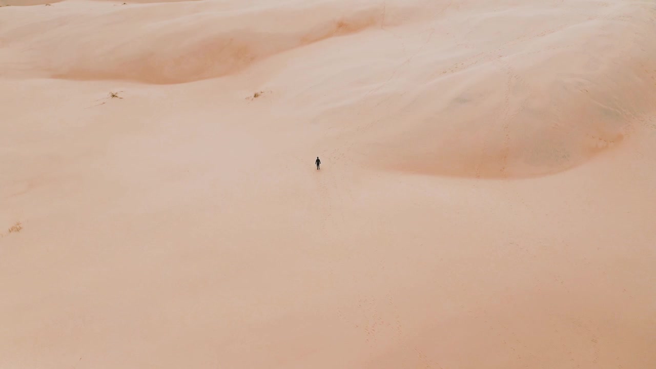 Vista aerea dall'alto di un uomo che cammina da solo sulle dune di sabbia