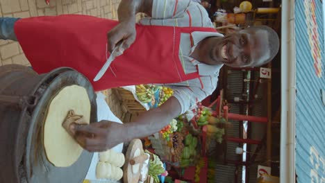 vertical - man frying chapati at african market