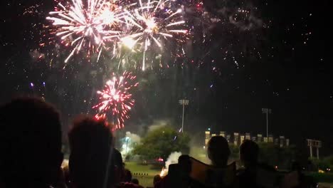 Un-Final-De-Fuegos-Artificiales-Con-Gente-Mirando-A-Orillas-Del-Río-Arkansas-En-Wichita,-Kansas