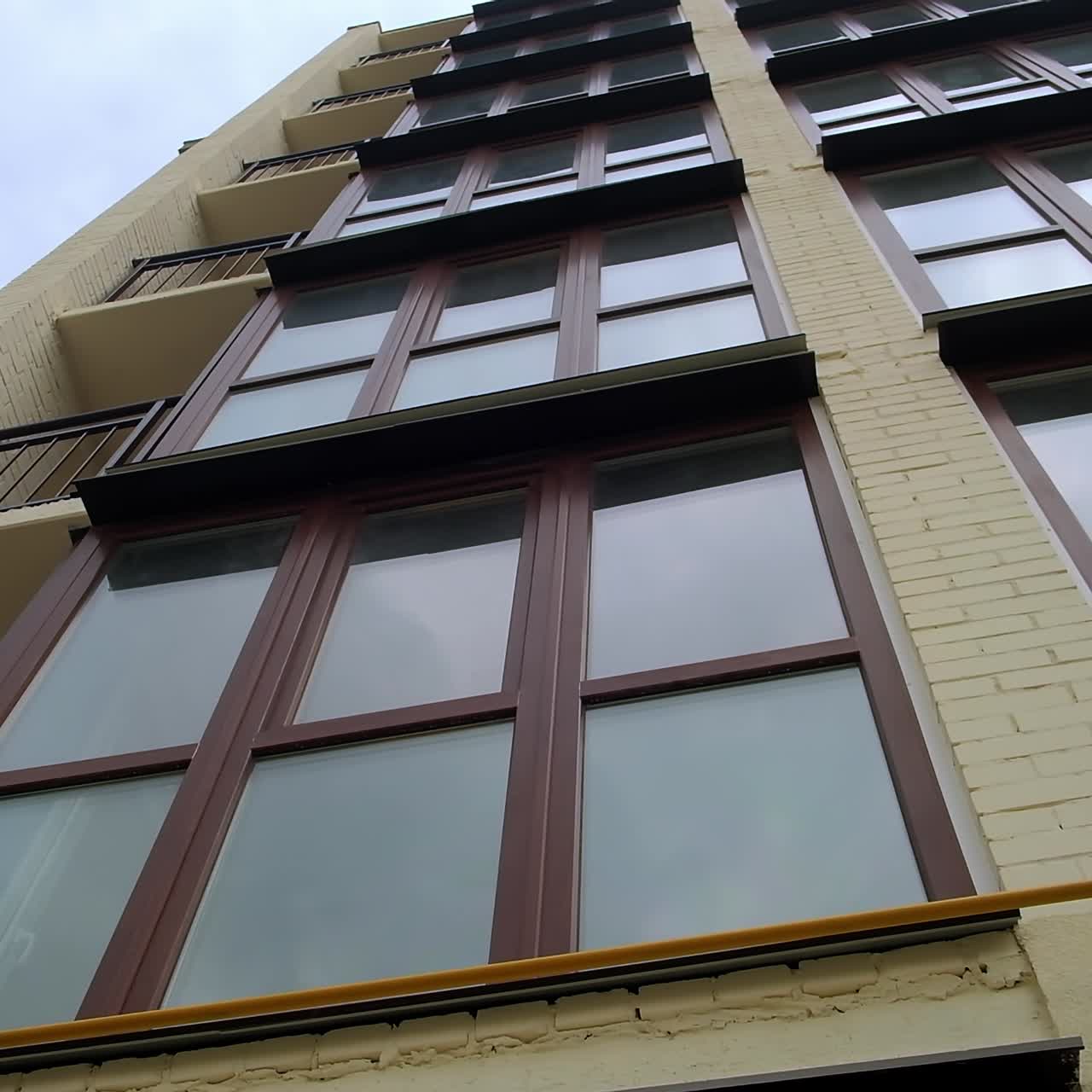 Balconi con vetrate e balconi aperti sulla facciata di un edificio residenziale di nuova costruzione. Abitazioni contemporanee sullo sfondo di un cielo grigio. Visuale dal basso
