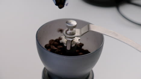 close up footage of coffee beans being poured into a hand grinder