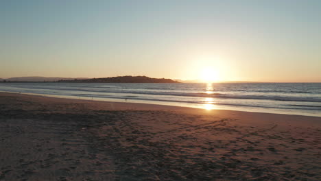 Punto-De-Vista-A-Lo-Largo-De-La-Playa-Iluminada-Por-La-Puesta-De-Sol-En-Tongoy-En-Puerto-Velero-Con-Olas-Rompiendo-Lentamente